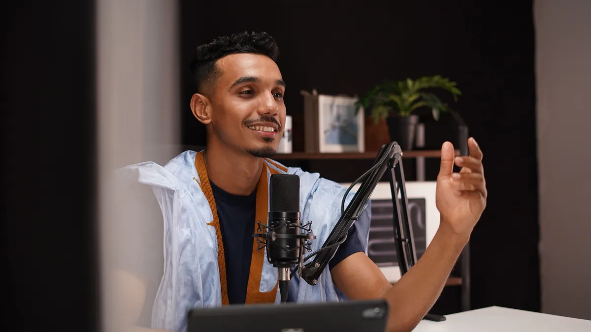 A podcast host talking into a boom microphone in his home studio.